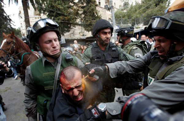 Israeli border police officers use pepper spray as they detain an injured Palestinian protester during clashes on Land Day in March
